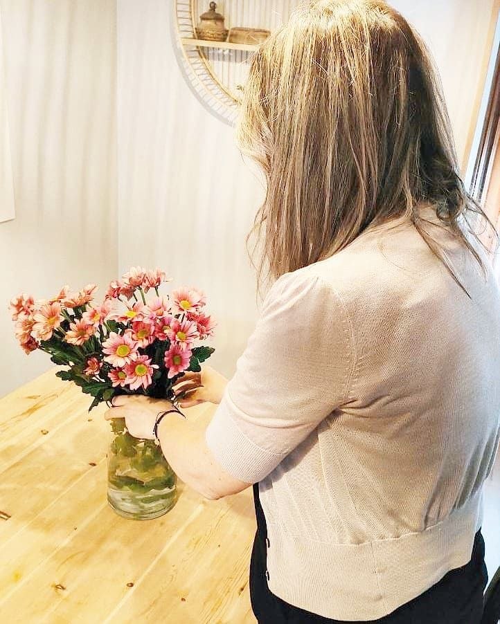 Olga col·locant flors sobre una taula de fusta
